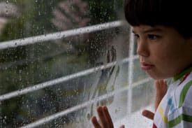 Sad boy stairing out of window