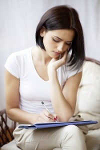 Woman writing on notepad to do list at home